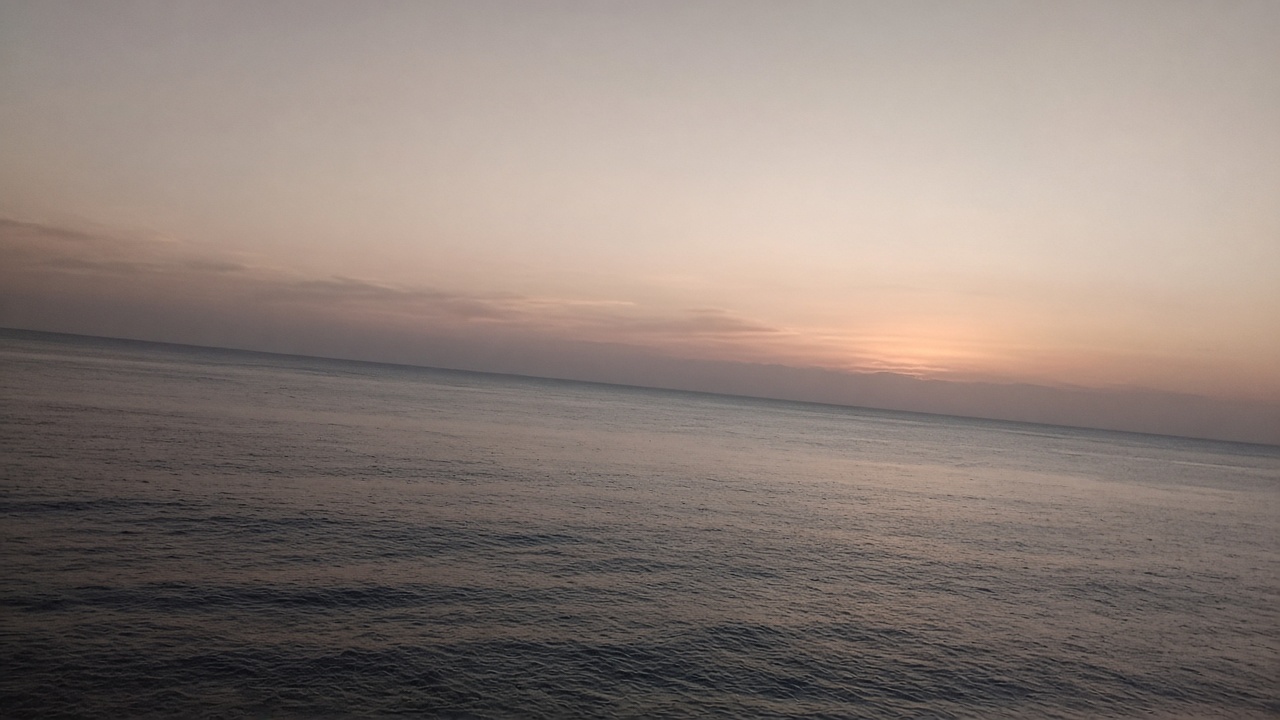 A dusk seascape with the horizon clearly tilted, sloping down toward the right